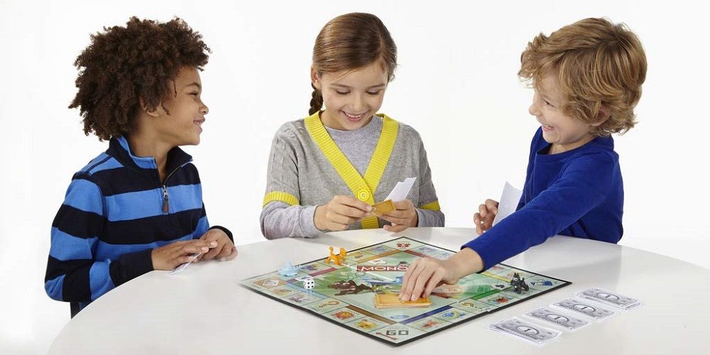 Mejores juegos de mesa con números - tres niños juegan Monopoly